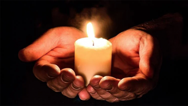 Hands holding a small candle (Myriams-Fotos / Pixabay)